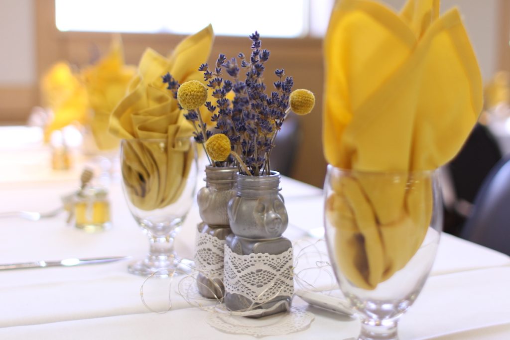 Wedding table setting with yellow napkins and honey bear bud vases